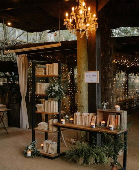 Mobiliario de madera decorado con libros antiguos, cajas rústicas y velas encendidas en un espacio interior de la finca.