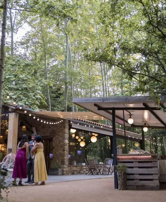 Invitados charlando en una zona exterior de la finca durante una celebración de bodas en la naturaleza.